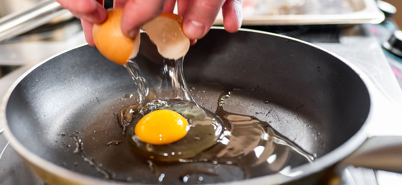 Person cracking egg in pan.