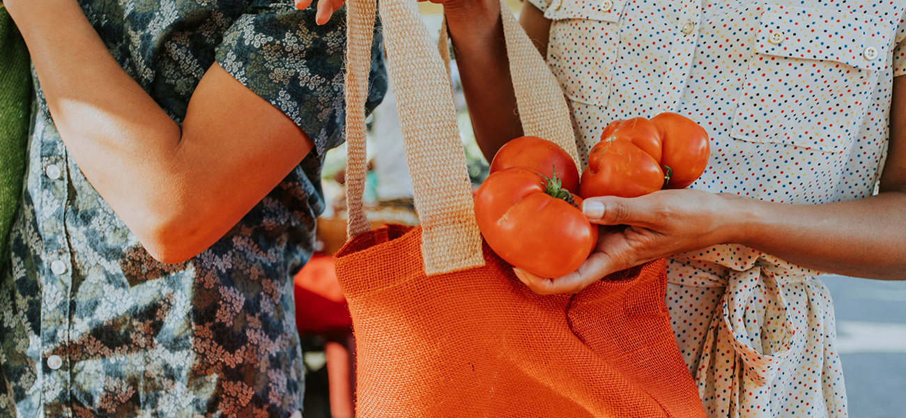 Lady buying fresh tomatoes at the farmer&rsquo;s market.