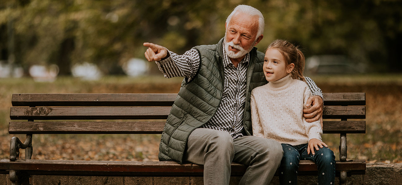 Grandpa and granddaughter bird watching at the park.