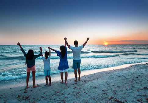 family on the beach at sunset with arms up