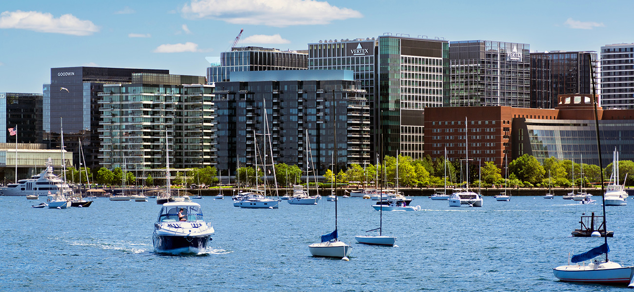 Boats in the water of the Boston Harbor with the Seaport District in the background.&nbsp;