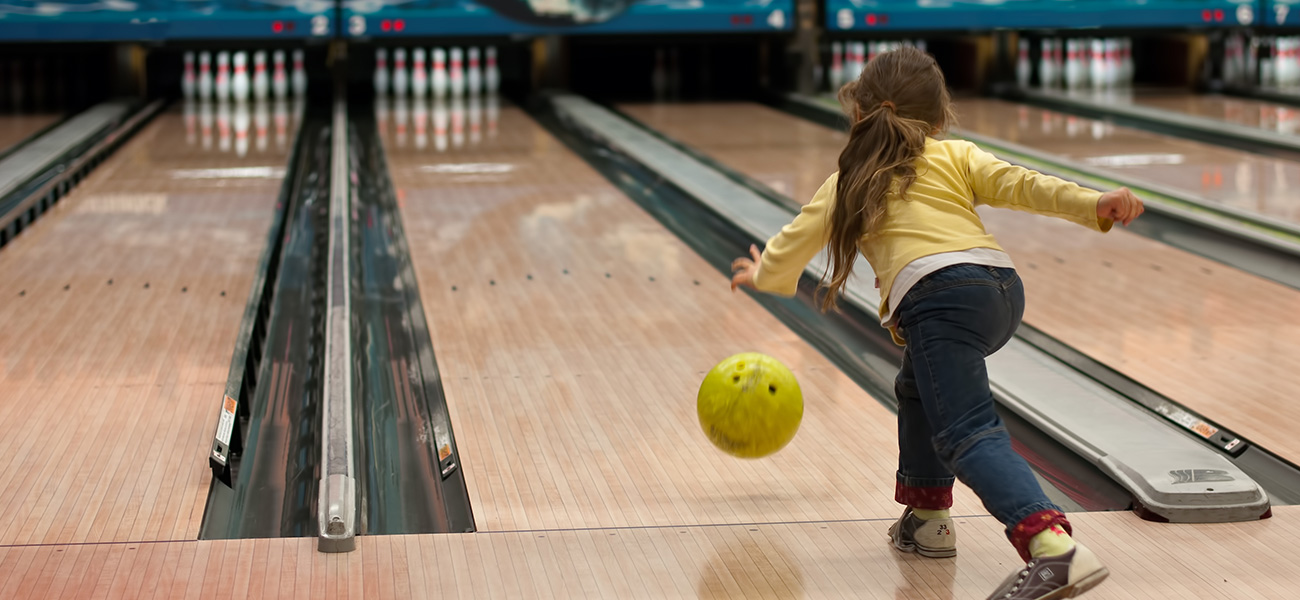 Girl bowling at a bowling alley.
